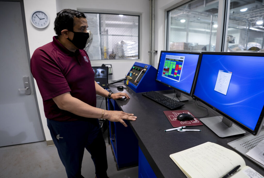 Suresh Pilai, Ph.D., in control room of eBeam center standing in front of two monitors