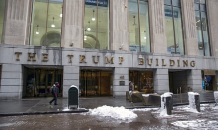 A limestone-faced office building with tall windows, with a snowy curbs and wet sidewalks.