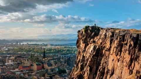 A man looks out over Edinburgh from Salisbury Crags cliff