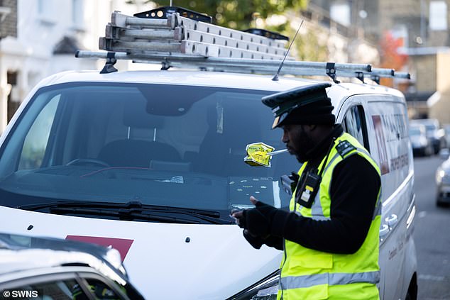 At traffic warden placing a parking ticket on a van parked in the shadow of Arsenal's Emirates Stadium, where drivers have to pay a £6.50-an-hour diesel levy on top of the base parking fee of between £2.50 and £6.30 an hour