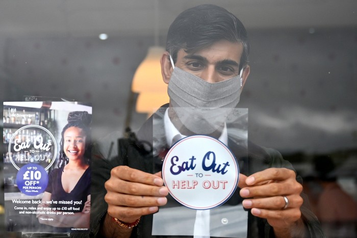 Sunak places an Eat Out to Help Out scheme sticker in the window of a business in Scotland in 2020