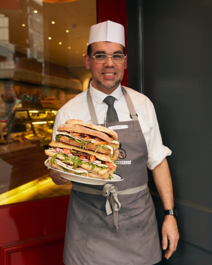 Robert, the general manager of the branch of Birleys on Old Broad Street, holding a pile of sandwiches on a plate