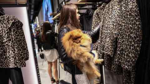 A shopper holding her dog browses clothing items at a store in Oxford Street, central London