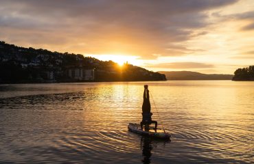 silhouette of person on boat doing headstand during sunset