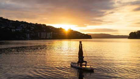 silhouette of person on boat doing headstand during sunset