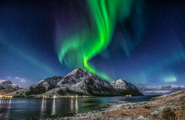 green aurora borealis over snow covered mountain