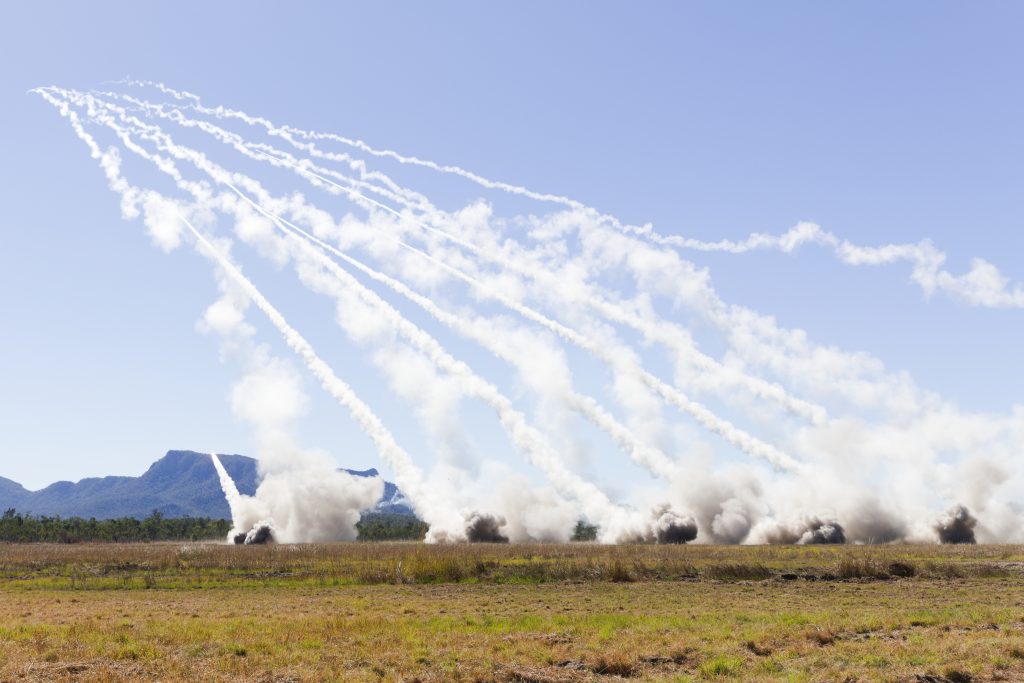 A combined battery of Singaporean, US, and Australian HIMARS launchers engages a target in a live fire exercise.