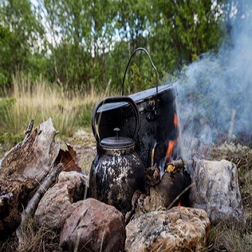 Kochen unterwegs. Topf und Wasserkanne im Lagerfeuer.