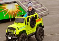 Spass im Freizeitpark. 2 jähriger Junge fährt mit einem grünen Elektroauto im Vergnügungspark.