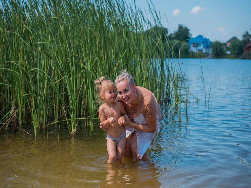 Baden im See. Eine Frau mit ihrem Kind in einem See.
