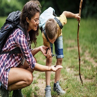 Wandern mit Kind. Mutter und ihr kleiner Sohn wandern durch den Wald. Sie benutzen eine Lupen und betrachten Insekten.