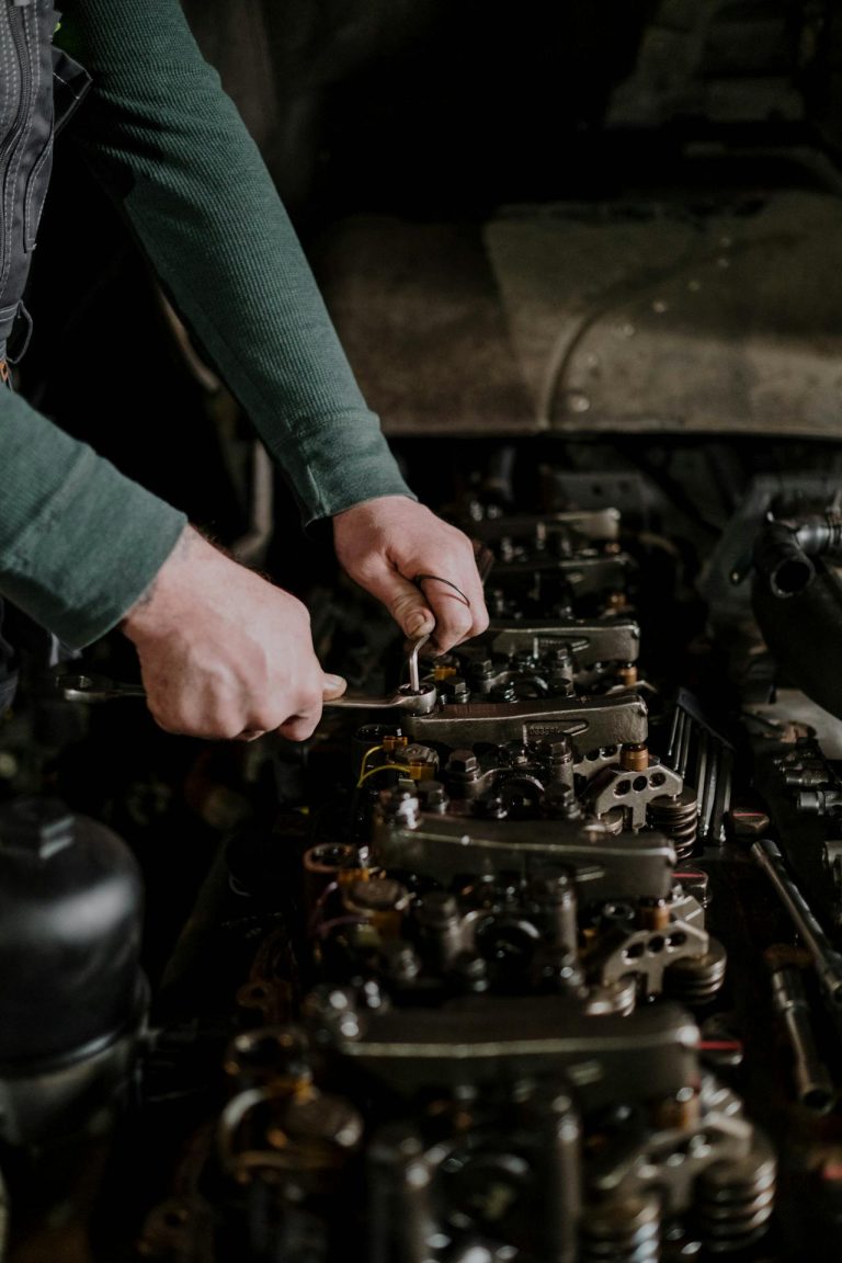 Monteur die werkt aan de motor van een voertuig met een steeksleutel