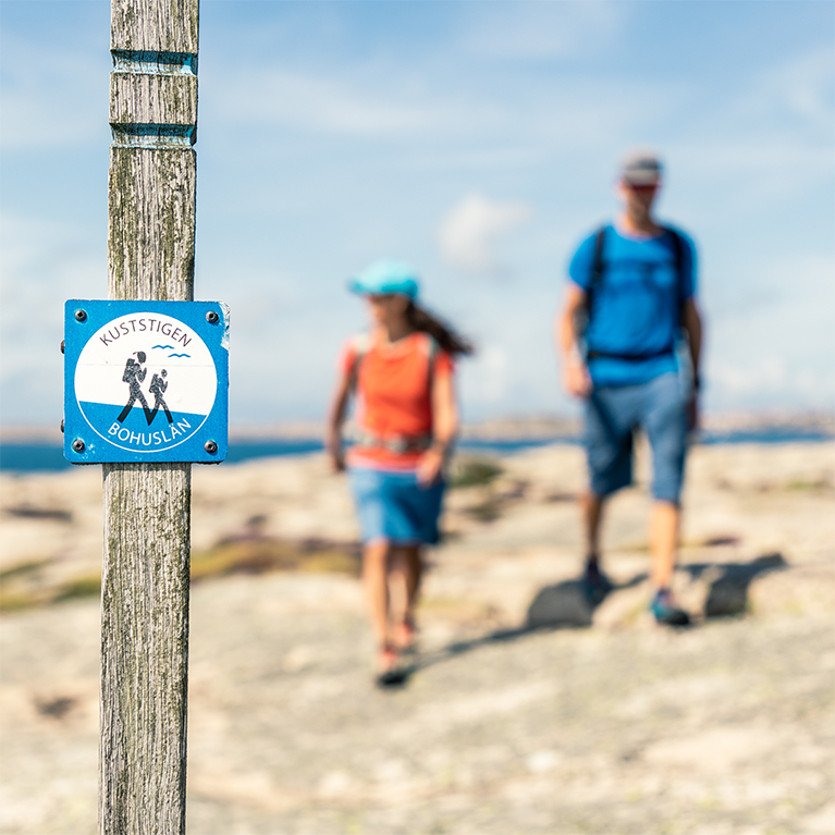 a man and a woman walking on cliffs with the sea in the background.