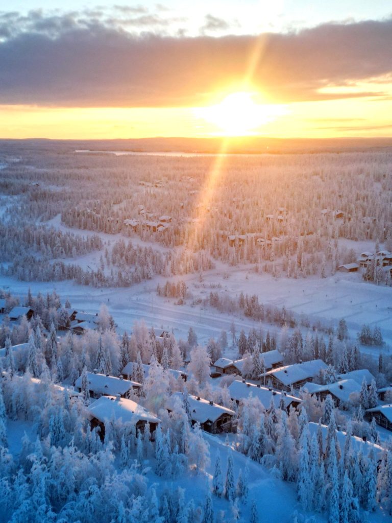 Ruka-Kuusamo: Your Ultimate Guide to Finland’s Natural Wonderland 2 Snow-covered cabins in Ruka, Finland, illuminated by a golden winter sunset, surrounded by a serene Arctic landscape