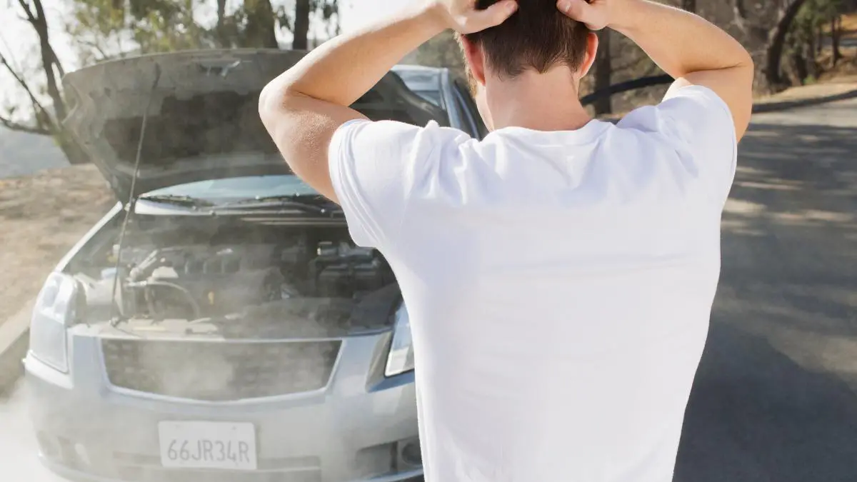 man in white t-shirt frustrated overheating car