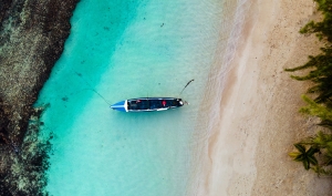 Aerial view of a boat on a Jamaican beach, something you'll be able to enjoy after settling into Jamaican life.