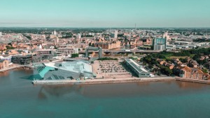 A panoramic view of a waterfront cityscape under a clear sky, illustrating urban development along the coast.