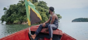 A man sitting in a boat with a Jamaican flag