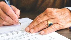 : A man signing a document on a table