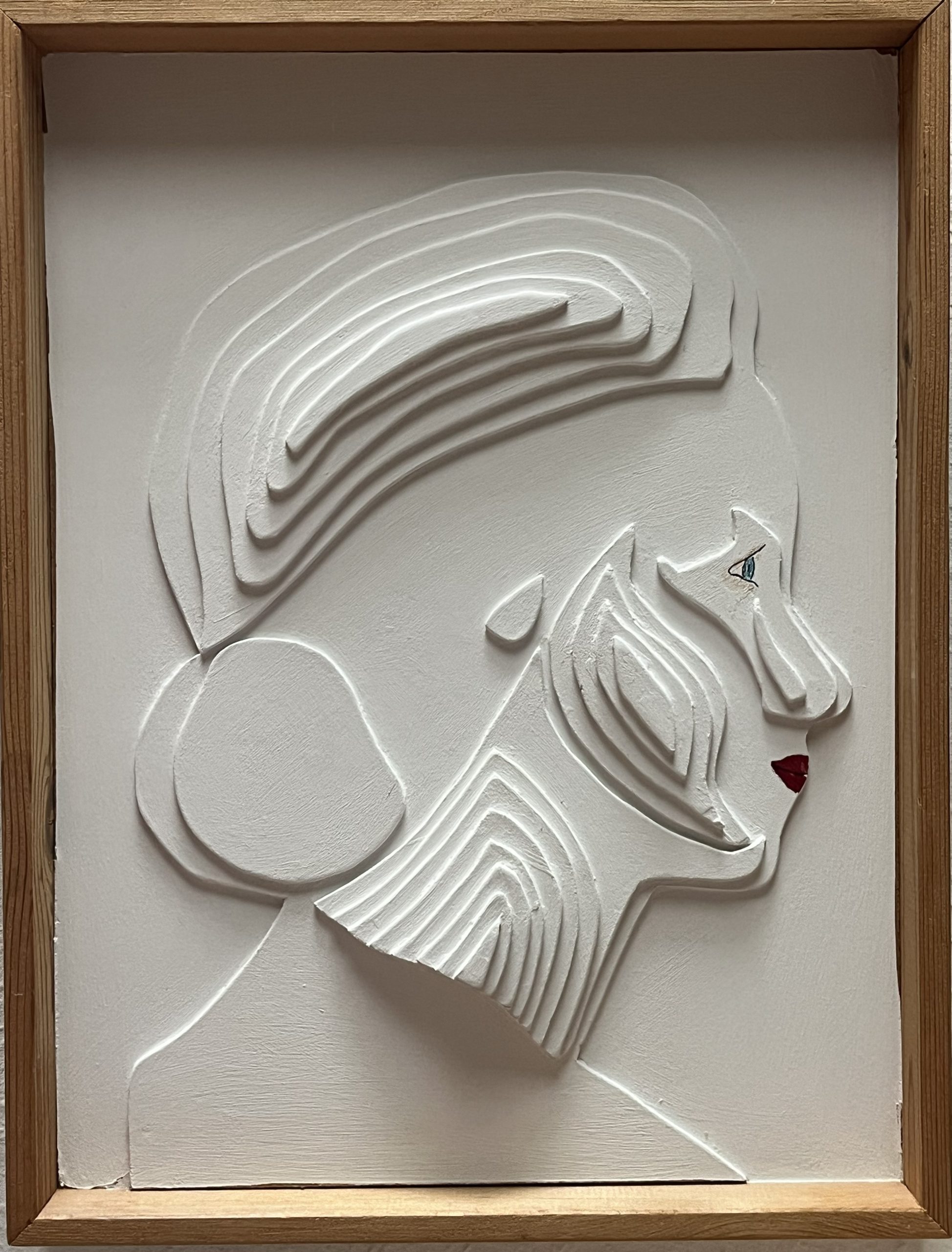 White bas-relief of a woman's profile with flowing hair, mounted in a wooden frame.