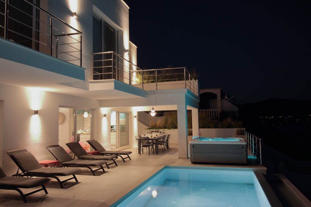 Outside pool terrace, night view, jacuzzi, sunloungers, wall washer lights