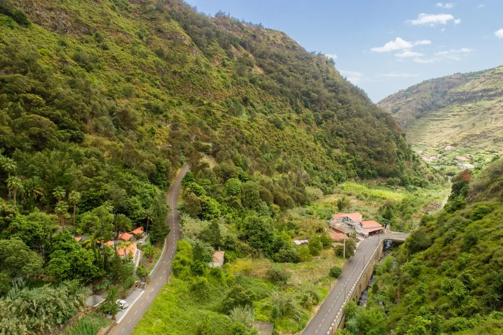 The Beauty of Madeira - Casas Da Terca. Beautiful hillside villa for holiday rent and booking - along a road in a valley with green trees and a house for holiday rent