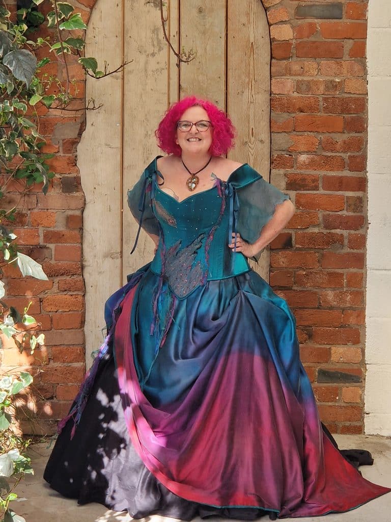 Berni Benton Celebrant, with a couple for a ceremony, in an elegant dress and with a mug saying 'shake your Bourbon'