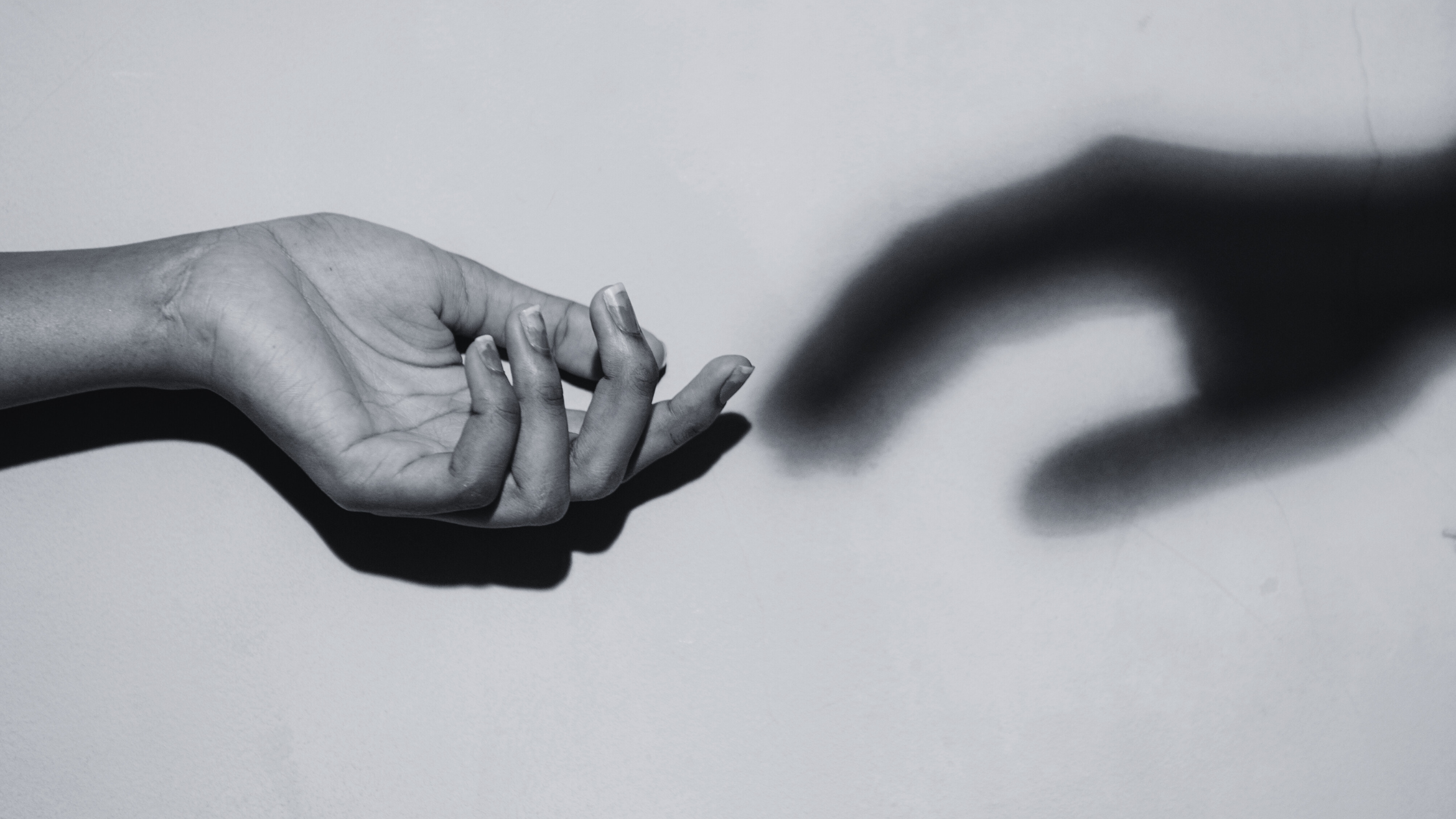 Imagen horizontal de mano y su sombra como tocandose