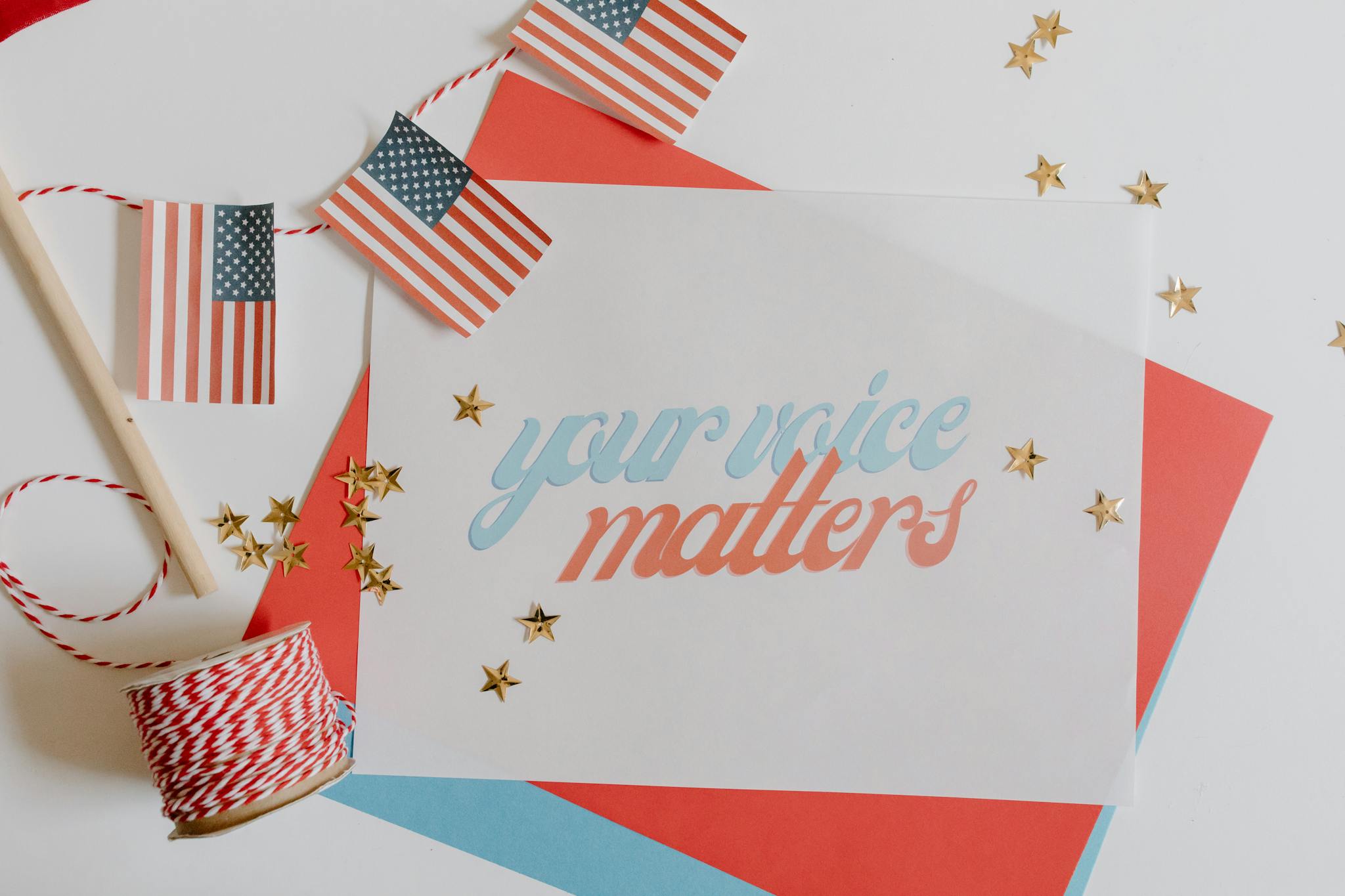 Flat lay of 'Your Voice Matters' with American flags and stars on a white background.