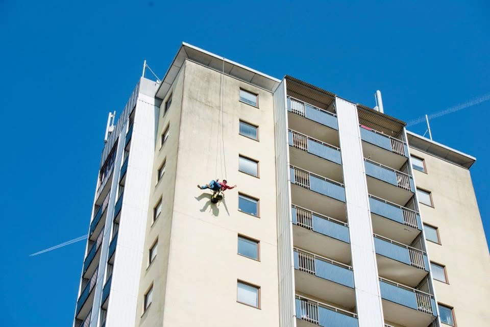 Yrkesklättrare hänger från byggnad