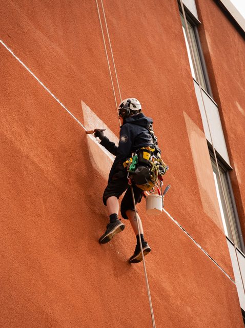 Reptekniker målar en vägg som är ny putsad.