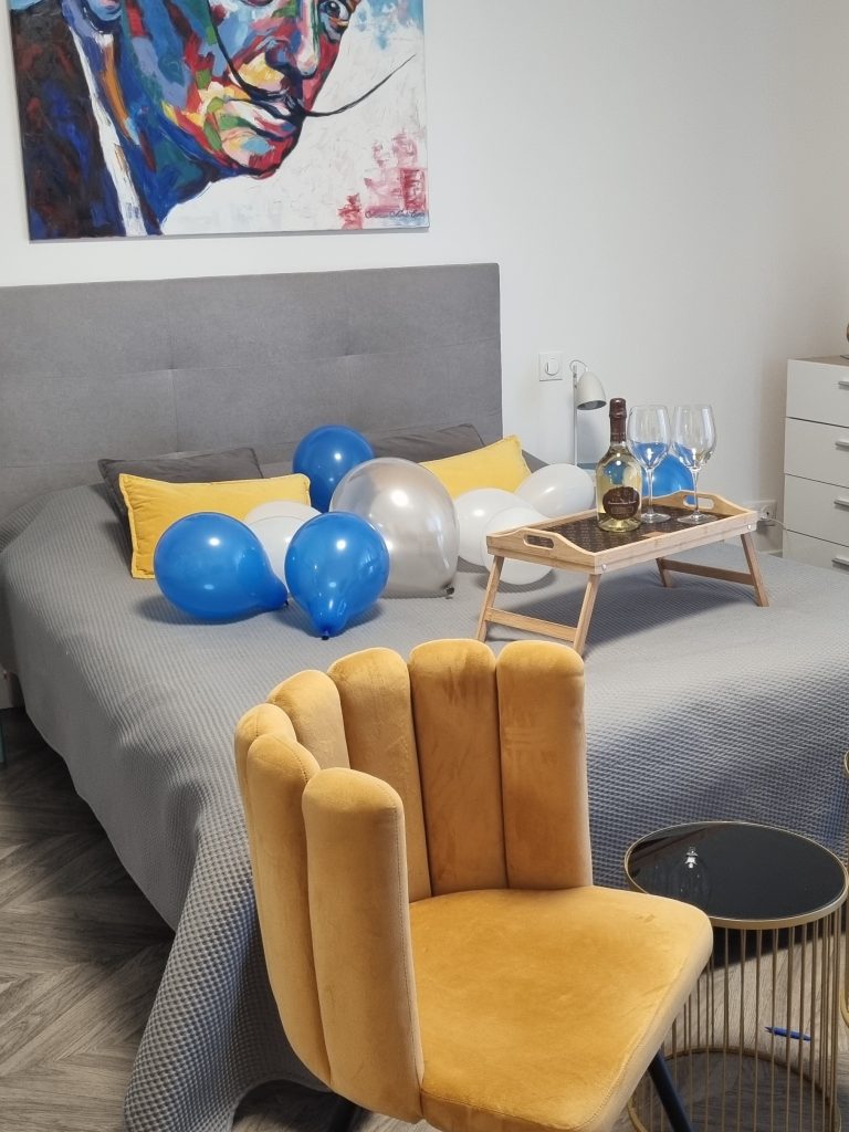 A bed with balloons and prosecco on it