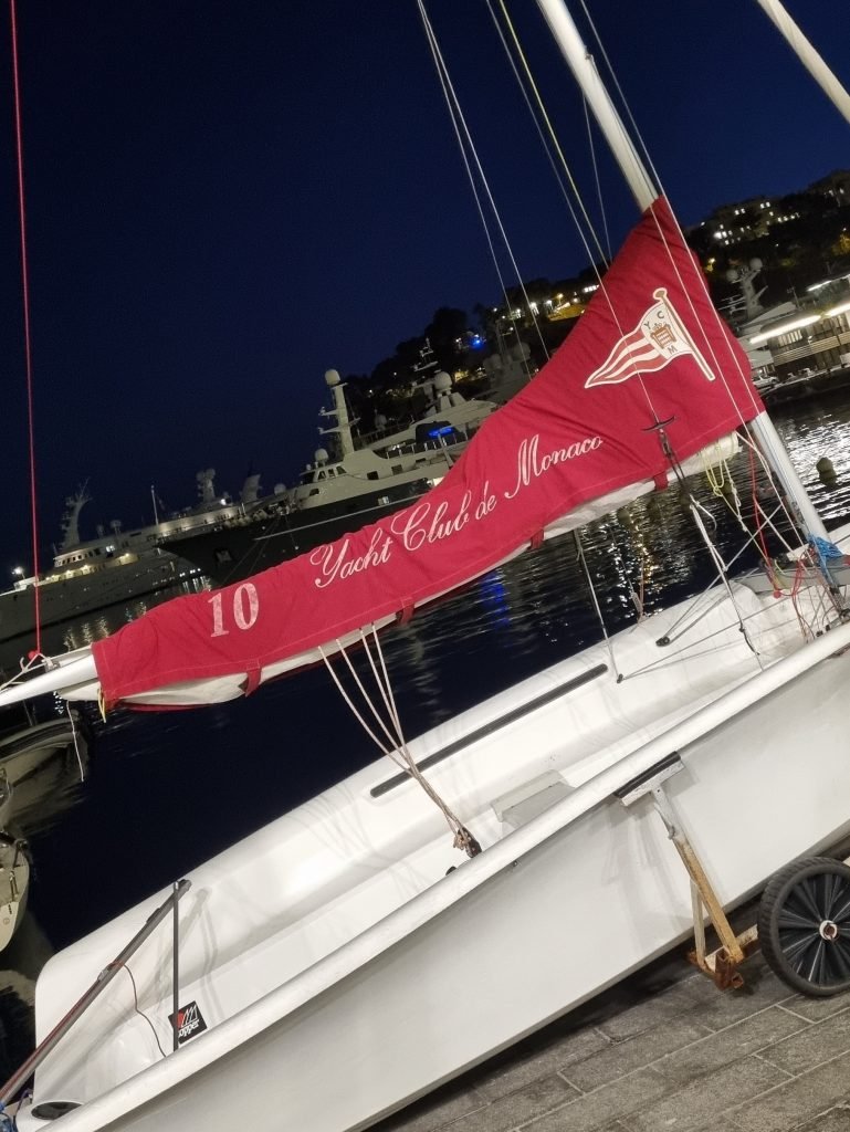 A boat on the shore with a Yacht Club De Monaco cover on it