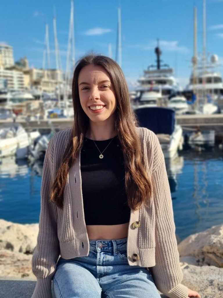 Charlotte wearing a cardigan and crop top sat at Monaco port