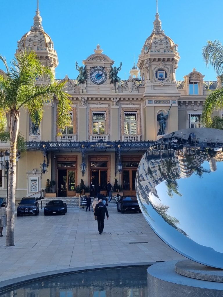 A grand casino with expensive cars parked at the front