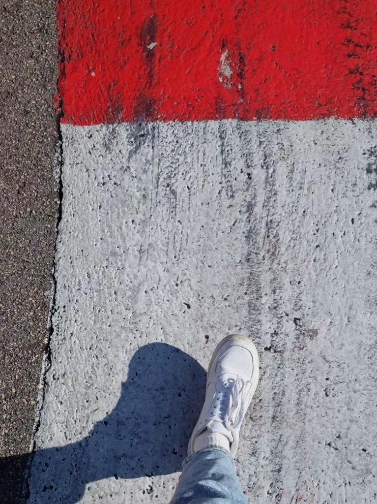 A white trainer walking along the red and white curbs painted for racing