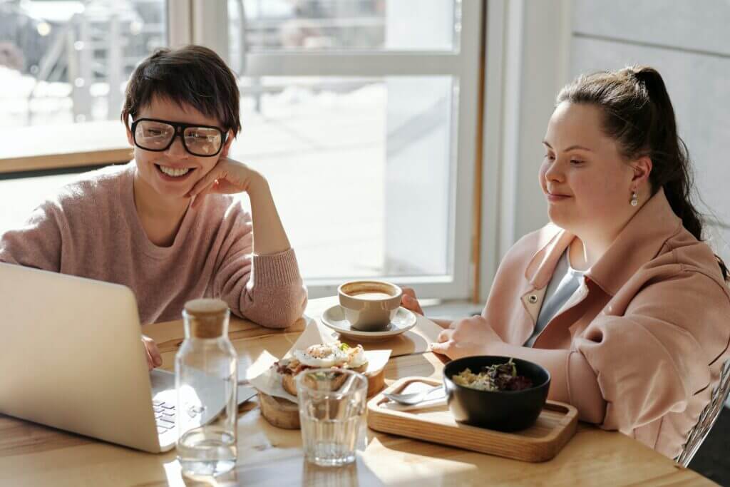 Zwei junge Frauen mit einem Computer am Cafétisch.