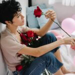 Frau, traurig, mit einer roten Rose und Luftballons sitzt auf dem Boden
