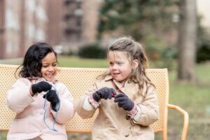 Zwei Mädchen spielen auf einer Bank.