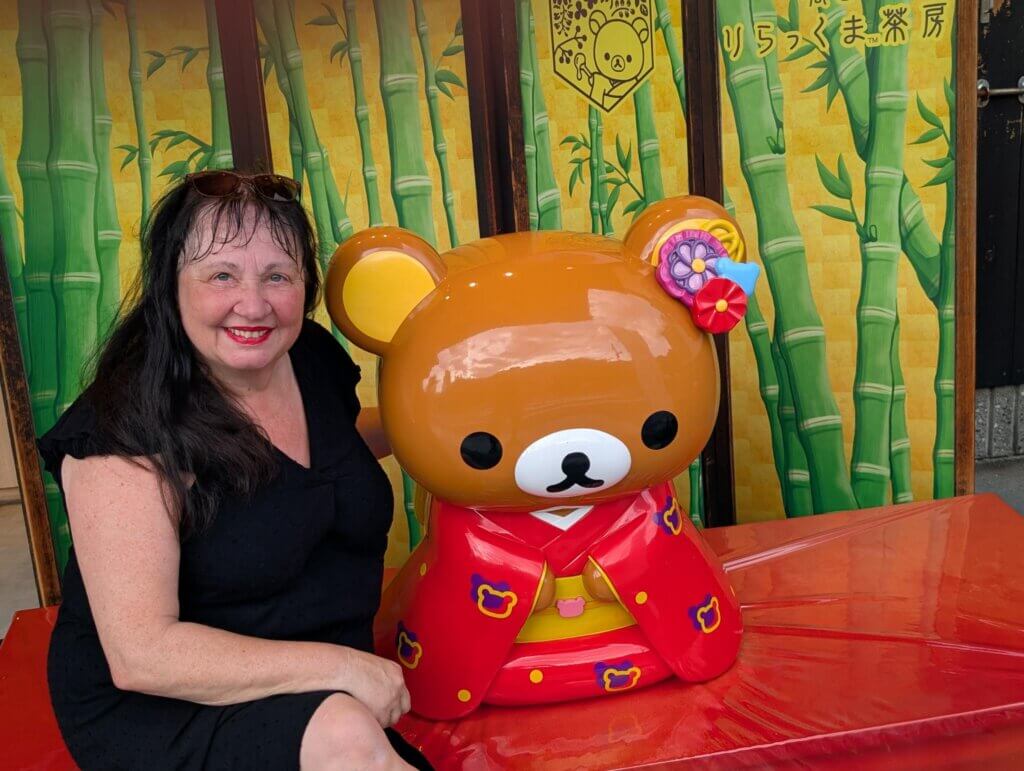 Christa sitzt neben einem großen Teddy-Bären