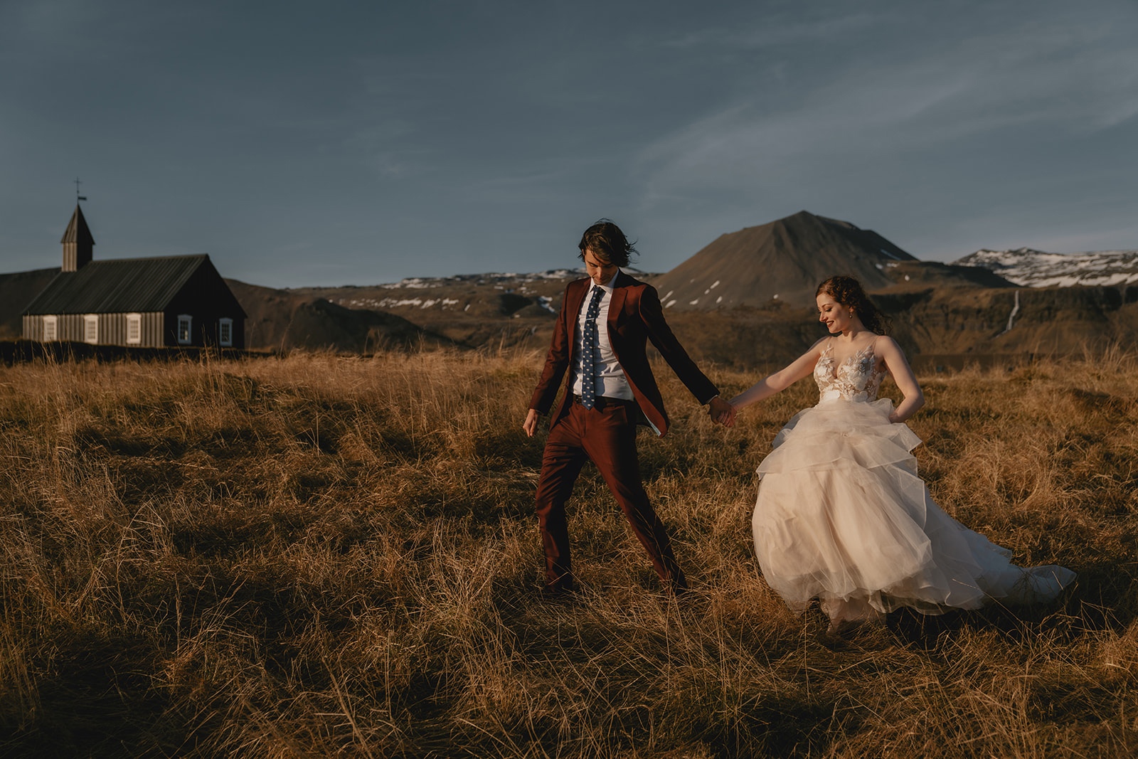 Newlyweds walking in the meadows around Budir Black Church in Iceland, photo by Christin Eide Photography