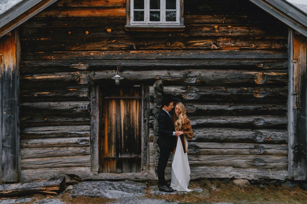 Winter elopement in Norway with falling snow. Traditional cabins. By Christin Eide Photography