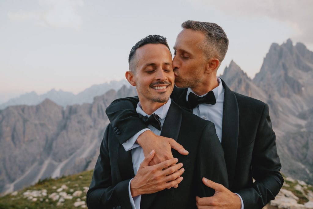 Two grooms embracing in the mountains of the Dolomites, photographed by Christin Eide Photography