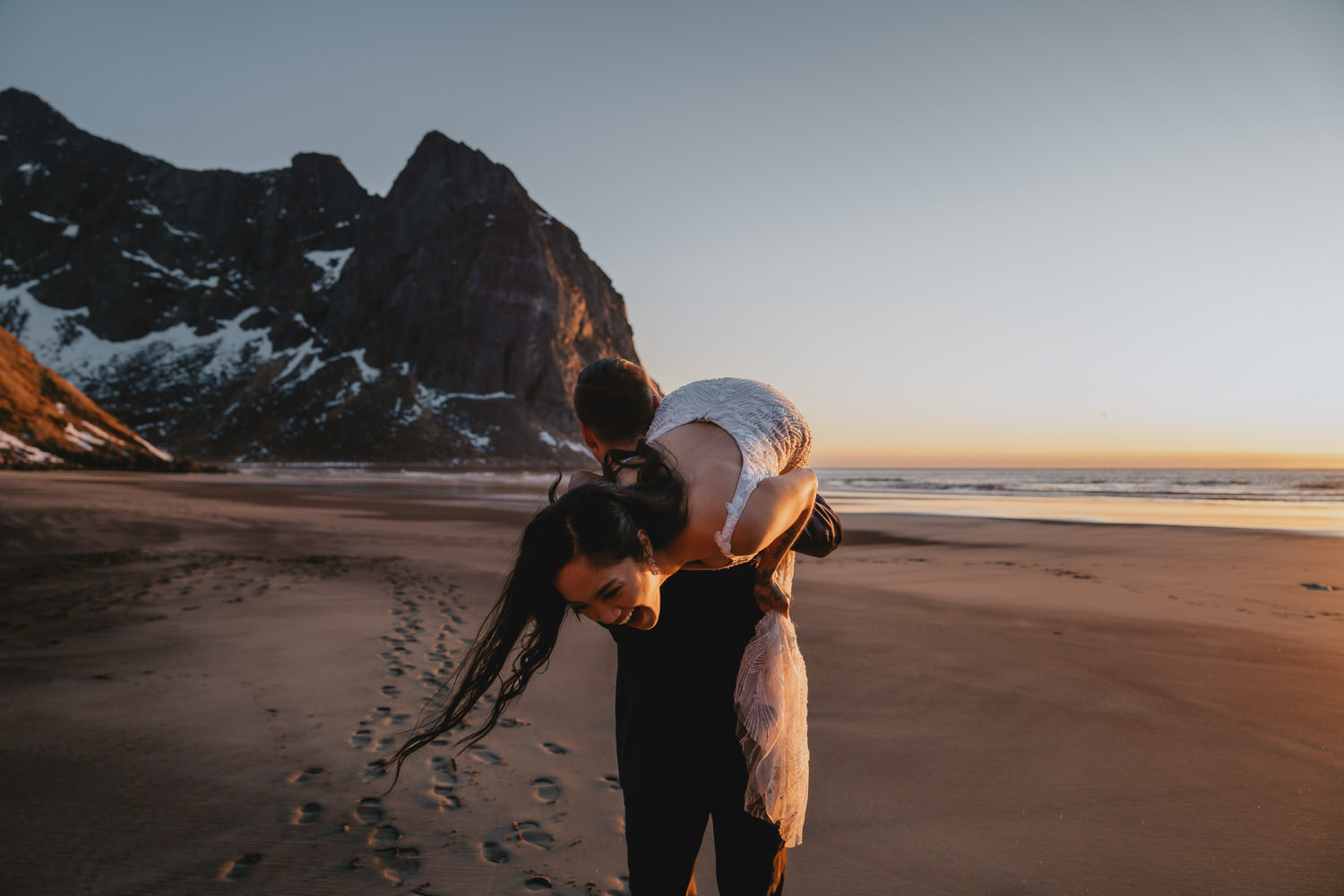 Groom carrying bride over his shoulder on the beach in Lofoten, Norway - photographed by Christin Eide Photography