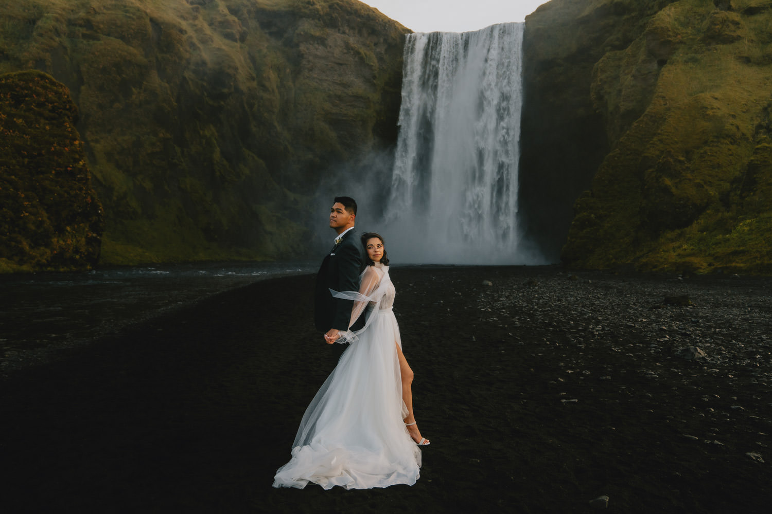 Stunning bride and groom in front of a waterfall during their adventure elopement in Iceland - photographed by Christin Eide Photography