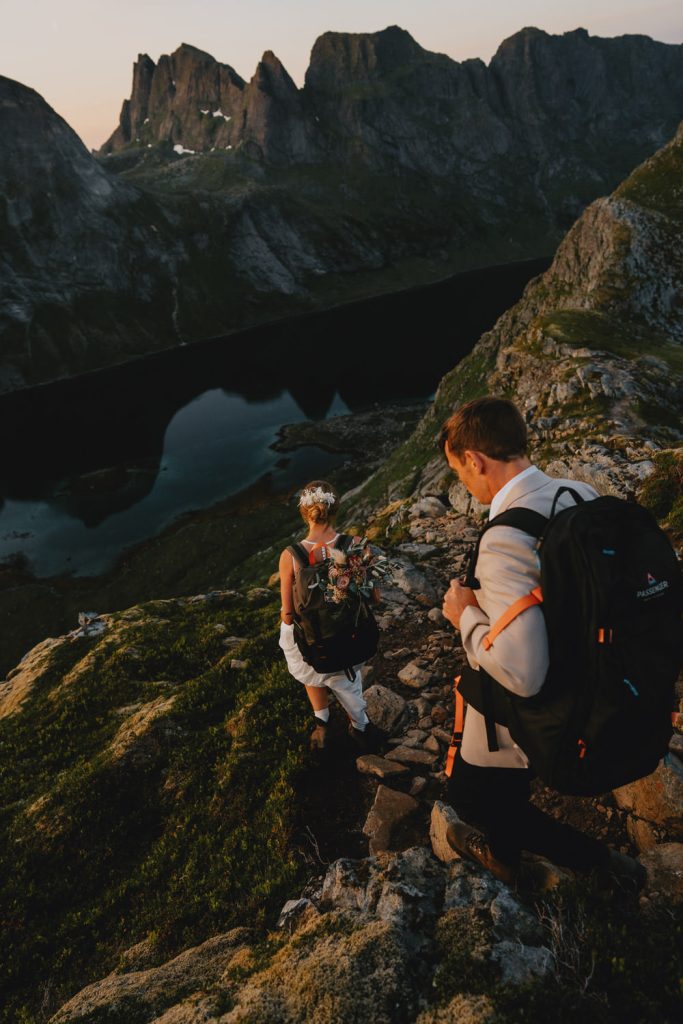 A bride and groom hiking during their adventure elopement in Lofoten, Norway - photographed by Christin Eide Photography