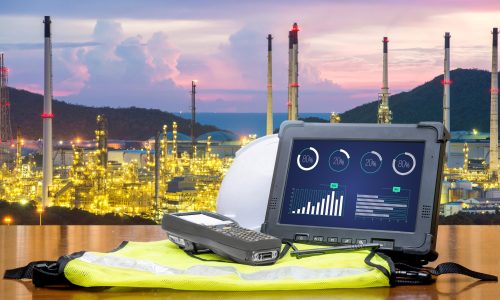 Smart factory - Rugged computers tablet in front of oil refinery industry.