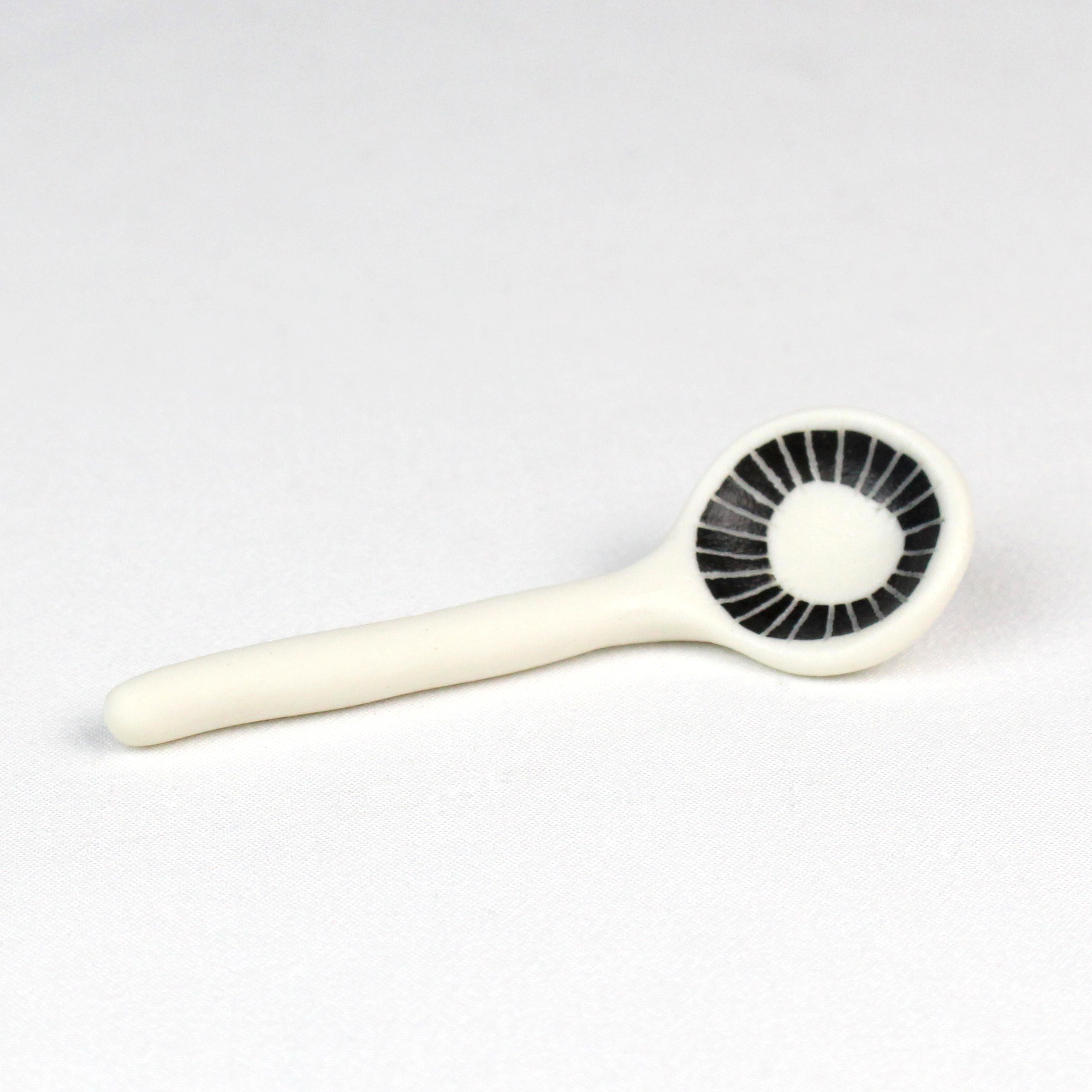 Small porcelain spoon with sgraffito decoration and transparent glaze in bowl by Vicky Hageman