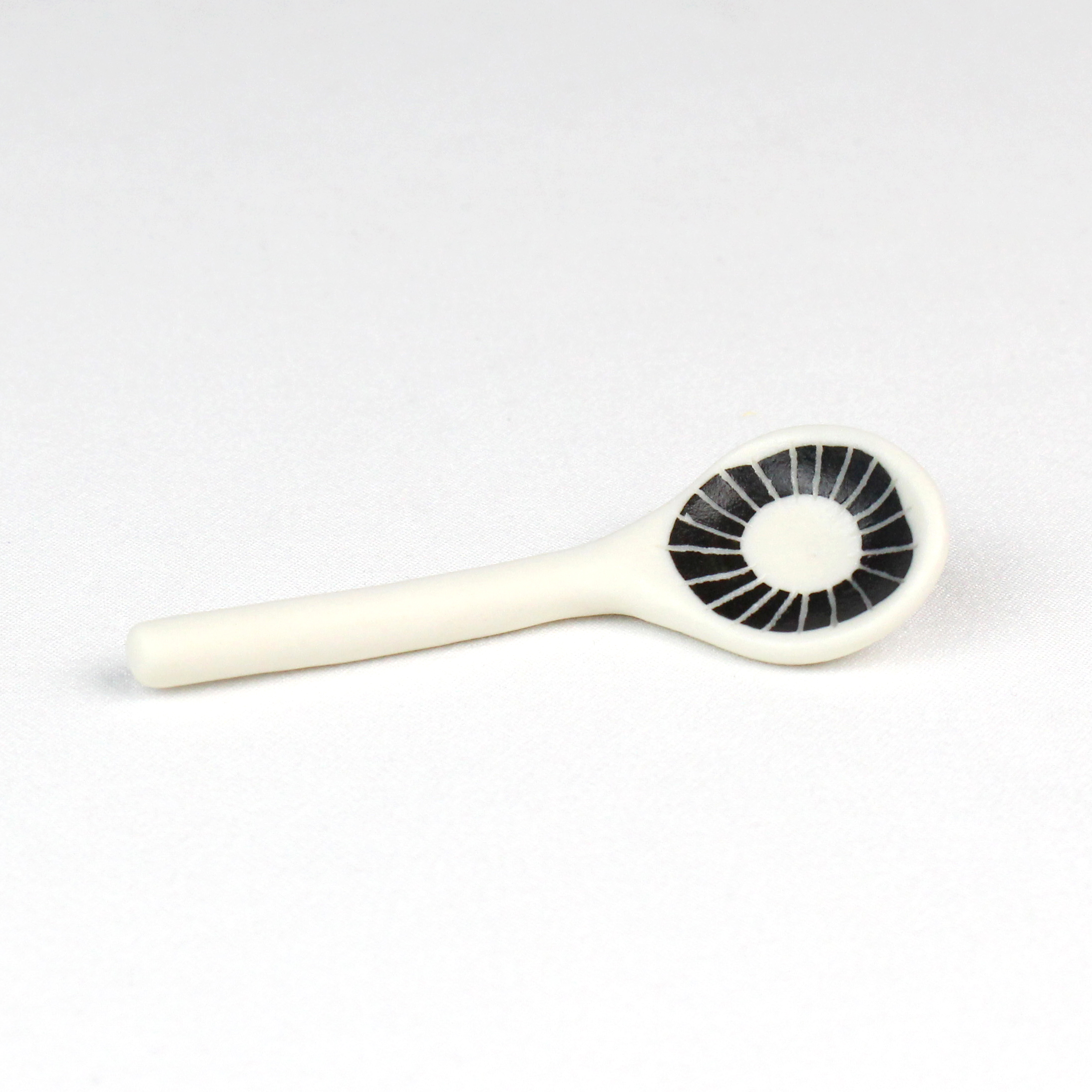 Small porcelain spoon with sgraffito decoration and transparent glaze in bowl by Vicky Hageman