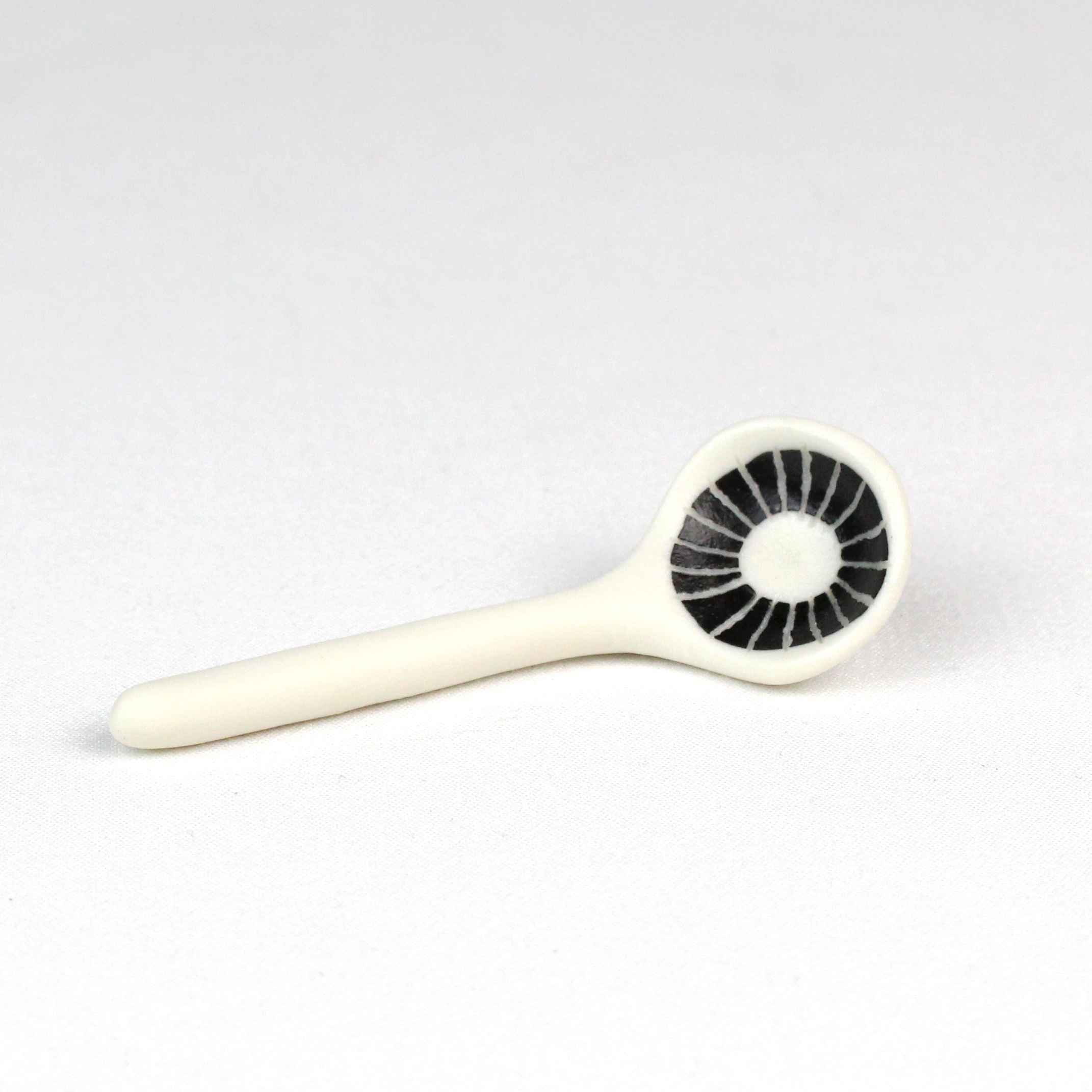 Small porcelain spoon with sgraffito decoration and transparent glaze in bowl by Vicky Hageman